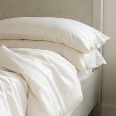 a bed with white sheets and pillows on it