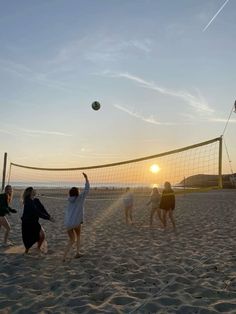 people playing volleyball on the beach at sunset