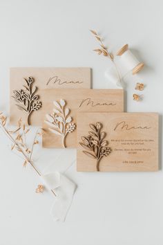 three wooden laser cut wedding cards with flowers and leaves on them, sitting next to each other