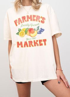 This Farmer's Market T-Shirt offers a relaxed adult fit and is made with heavyweight Comfort Colors for ultimate comfort. The trendy vintage retro design features a typography of "Farmer's Market - Locally Grown" with a colorful illustration of peach, lemon, and berry. Show your support for local produce while looking stylish and feeling comfortable. S:M:L:XL *Size Chart Available Garment Dyed Cotton 100% Machine Wash Delicate cycle with like colors Retro Faded T-shirt With Letter Print, Vintage Text Print T-shirt For Spring, Vintage Short Sleeve T-shirt With Lettering, Faded T-shirt With Text Print In Relaxed Fit, Faded T-shirt With Text Print And Relaxed Fit, Relaxed Fit Faded T-shirt With Text Print, Faded Short Sleeve T-shirt With Letter Print, Vintage Oversized Tops With Lettering, Faded Graphic Tee With Text Print