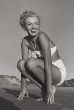 an old photo of a woman kneeling on the beach