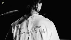 a person standing in front of a microphone with writing on the back of their shirt