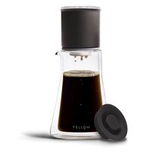 a glass coffee maker filled with liquid and topped with a black lid, on a white background