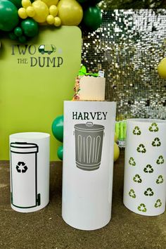 three trash cans sitting next to each other on top of a table with balloons in the background