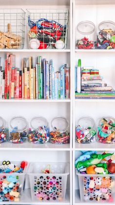 a white bookcase filled with lots of books next to bins full of toys