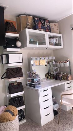 a white desk topped with lots of drawers next to a shelf filled with purses