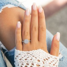 a woman's hand with a diamond ring on her left wrist and white nails