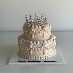 a three tiered cake with white frosting and beaded decorations on the top