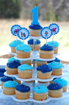 cupcakes with blue frosting are arranged on a cake stand for a first birthday party