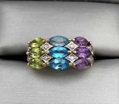 This 14K yellow gold ring features 3 rows of prong-set, genuine, natural, 5.5x3mm marquise-cut, gemstones.   Peridot, Blue Topaz, and Amethyst.  The gemstones have been tested with a gemstone tester.   White gold illusions with tiny diamonds accent the gemstones.  The setting measures 9.2mm tall and 19mm wide  Specs:  Metal: 14K Yellow Gold Hallmarked: (14K)   Ring Size: US 6 3/4   Ring Weight: .13 oz. or 4.1 grams  IMPORTANT NOTICE:  If you would like to inquire about re-sizing, please message us and wait for a response before you finalize your purchase.  If the re-sizing is possible we then add the re-sizing fee to your total before you finalize your purchase.  We do not accept returns or exchanges. Our items are accurately described and guaranteed. Contact us if there is an issue with y Yellow Gold Multi-stone Topaz Ring, Multi-stone Amethyst Ring In Yellow Gold, Fine Jewelry Yellow Gold Multi-stone Topaz Ring, 14k Gold Multi-stone Topaz Ring, 14k Gold Multi-stone Purple Amethyst Ring, Tiny Diamond, Marquise Cut, Diamond Rings Bands, Birthstone Ring