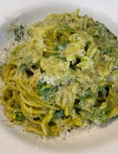 a white plate topped with pasta covered in pesto