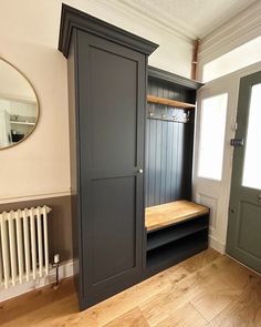 an empty room with a wooden floor and black cupboards on the wall, next to a radiator