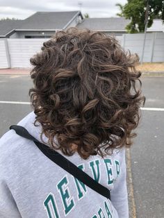 the back of a person's head with long curly hair and grey hoodie