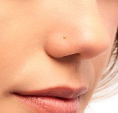 a woman's nose has a tiny yellow dot on the tip of her nose