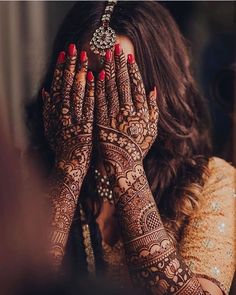 a woman holding her hands up to her face with henna on top of her