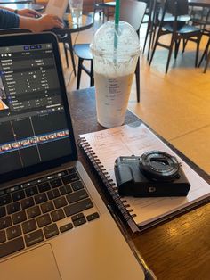 an open laptop computer sitting on top of a wooden table next to a cup of coffee