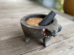 an old mortar bowl filled with food on top of a wooden table