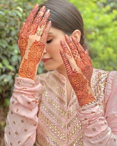 a woman holding her hands up to her face with henna on top of it