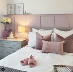 a pair of pink slippers sitting on top of a white bed next to pillows