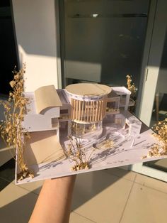 someone holding up a model of a building