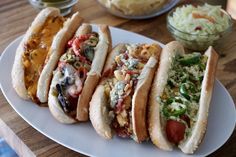 four hot dogs are on a plate with coleslaw