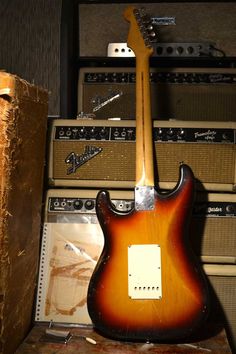 an electric guitar sitting on top of a wooden table next to amps and boxes