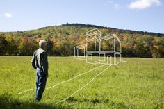 a man standing in the middle of a field looking at a house drawn on it