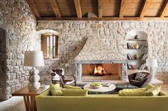 a living room filled with furniture and a fire place next to a stone wall covered in books