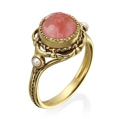 a gold ring with a pink stone surrounded by pearls