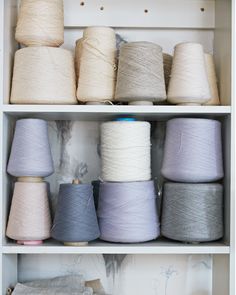 several skeins of yarn are on shelves in a room with white walls and drawers