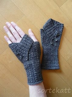 a pair of gray knitted gloves sitting on top of a wooden floor