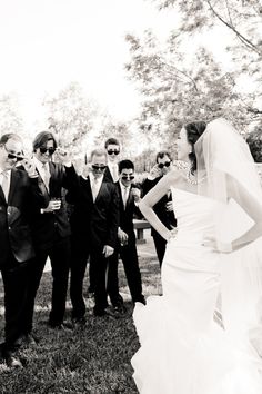 a bride and groom standing in front of their wedding party