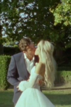 a man in a suit and tie kissing a blonde haired woman wearing a white dress