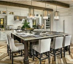 a large kitchen with white cabinets and an island in the middle is surrounded by chairs