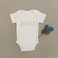 This simple outfit will suit your little 'peanut' perfectly! The Details •Screen printed in-house using phthalate-free ink. •Garment is made from 100% soft organic cotton. •No harmful chemicals, pesticides, or artificial dyes. •Sustainably sourced and ethically produced. •As with any organic cotton, some fabric imperfe Neutral Baby Onesies, One Piece Clothes, Handmade Kids Clothes, Funny Baby Gifts, Urban Baby, Artificial Dyes, Bodysuit Outfit, Handmade Baby Clothes, Funny Baby Clothes