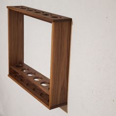 a wooden shelf mounted to the side of a white wall with holes in it that are made out of wood