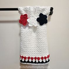 a crocheted towel hanging from a hook on a white wall with black and red trim