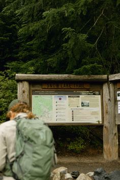 a person with a backpack standing in front of a sign that says snow peak trail