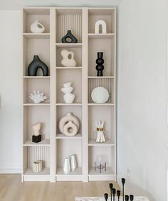 a living room filled with lots of white shelves covered in black and white vases