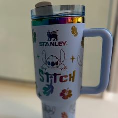 a stainless steel travel mug with colorful stickers on it