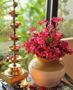 a vase filled with pink flowers sitting on top of a table next to a candle