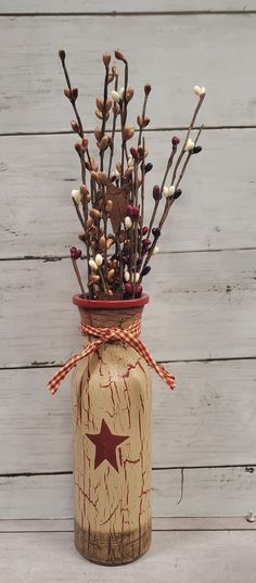 a vase filled with branches and flowers on top of a white wooden table next to a wall