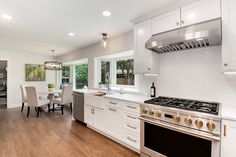 a kitchen with an oven, stove and dining room table in the backround