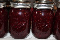 four jars filled with red liquid sitting on top of a table