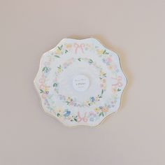 a white plate with floral designs on the bottom and lettering in pink, blue, yellow and green