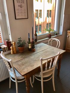 a table with chairs and bottles of wine on it in front of a large window