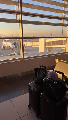 two pieces of luggage sitting on top of a tiled floor next to an airport window