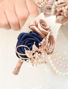 a close up of a person's hand holding a flower brooch