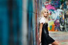 a woman leaning against a wall with graffiti painted on the walls behind her and looking at the camera