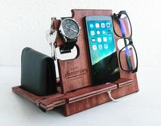 an iphone, watch, and glasses are on a wooden stand with sunglasses in it